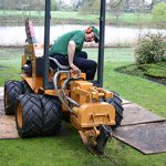 Contractor using a trenching machine to install garden irrigation pipework